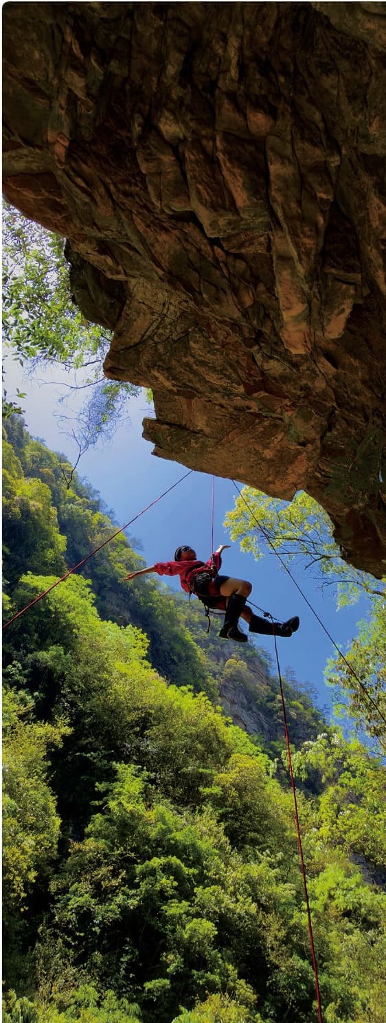Sandstone overhang, rope system and descending person in Baihutang