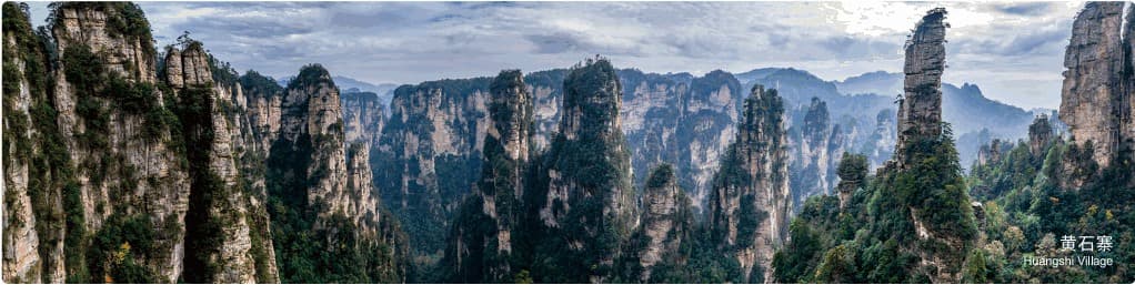 Official wide Huangshi Village panorama across sandstone towers and forested cliffs