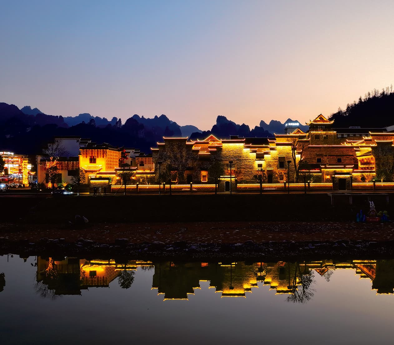 Wulingyuan riverside accommodation glowing at night in the official Tour Guide Manual.