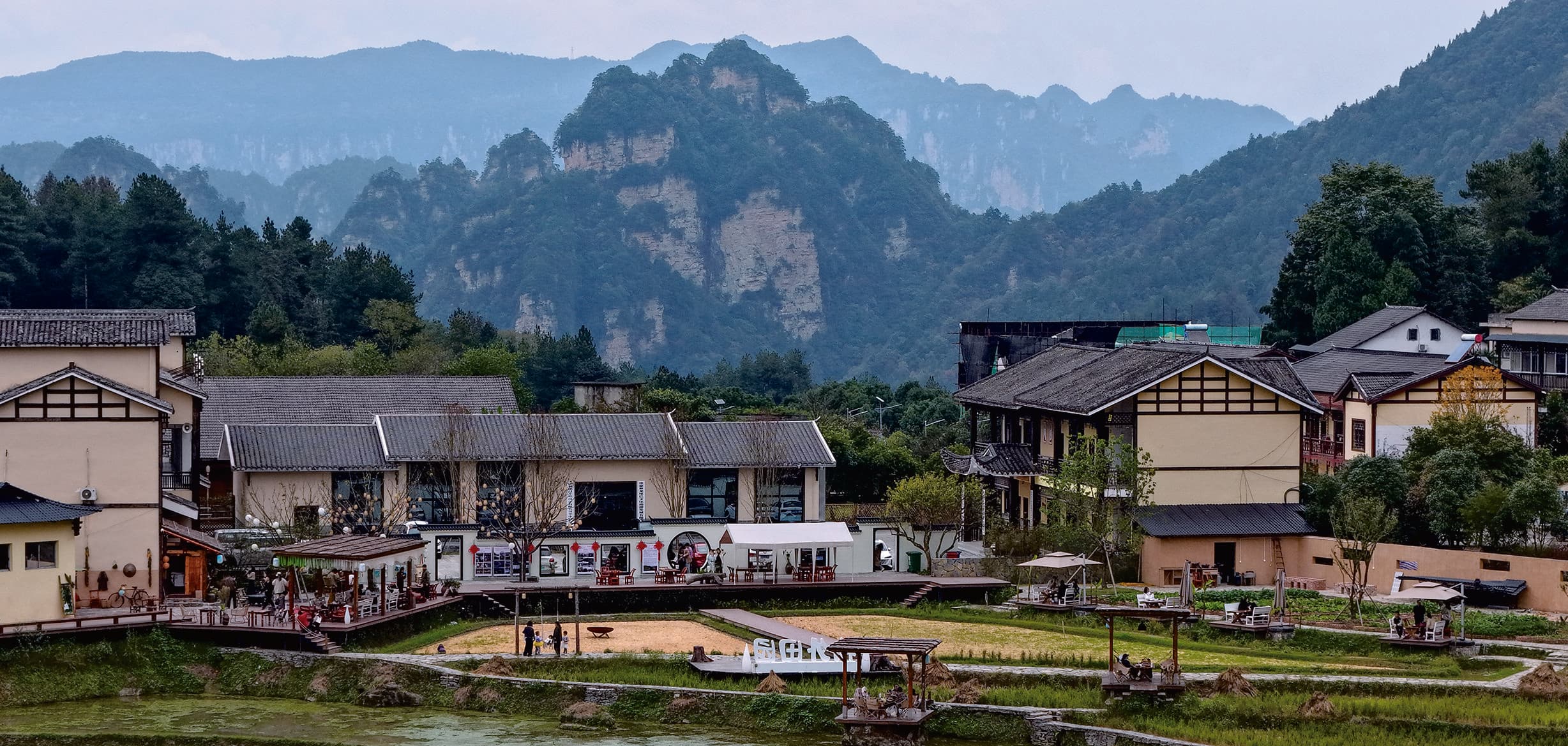 Wulingyuan accommodation lining a forested river in the official Tour Guide Manual.