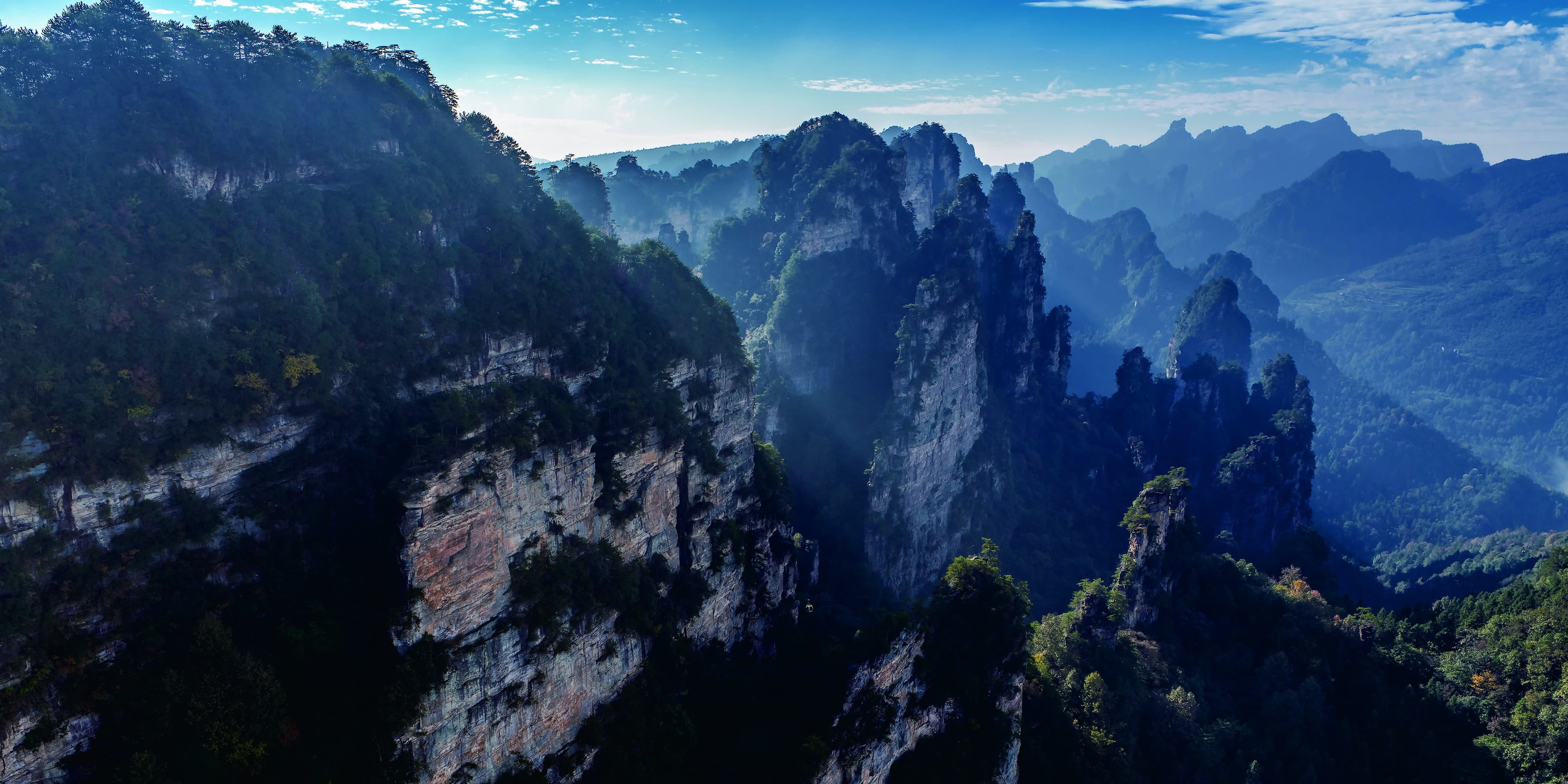 Zhangjiajie sandstone peaks and forested valleys beneath a clear sky in the official Tour Guide Manual.